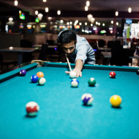 Stylish arabian man wear on jeans playing pool billiard on bar.